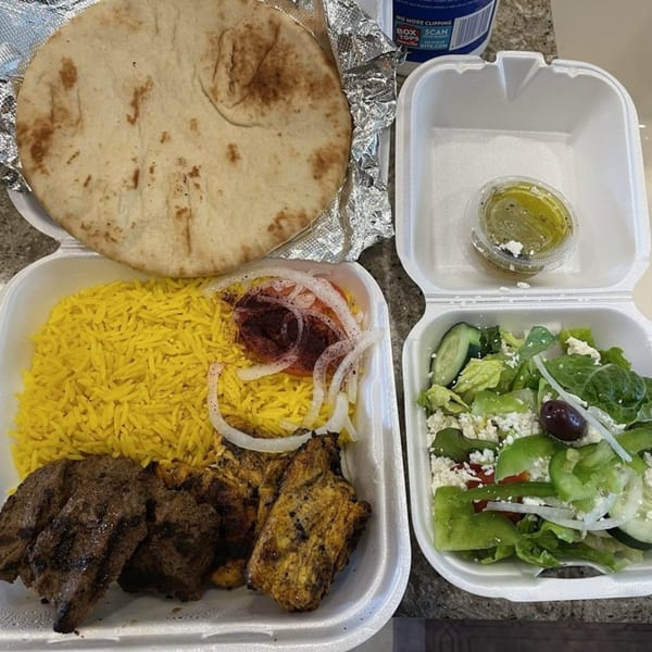 King Of Gyros Greek meal with pita, yellow rice, grilled meats, and a side salad.
