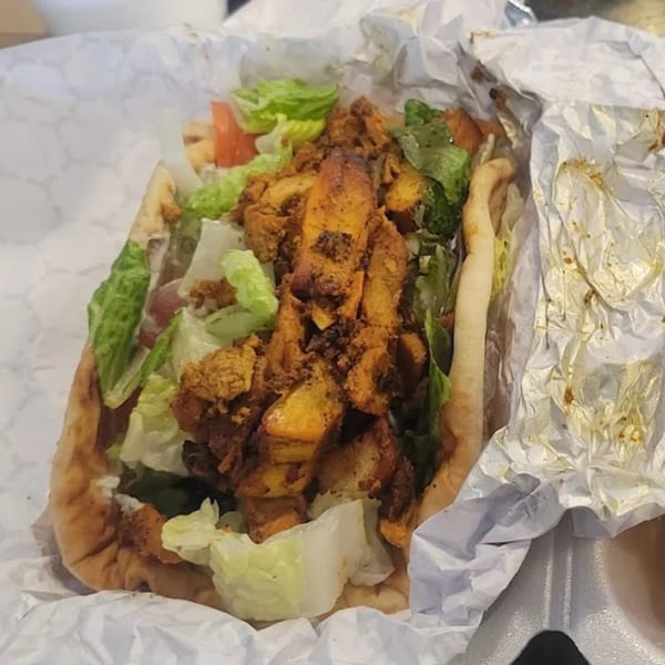 King Of Gyros' chicken gyro with lettuce and tomatoes, wrapped in paper and foil.