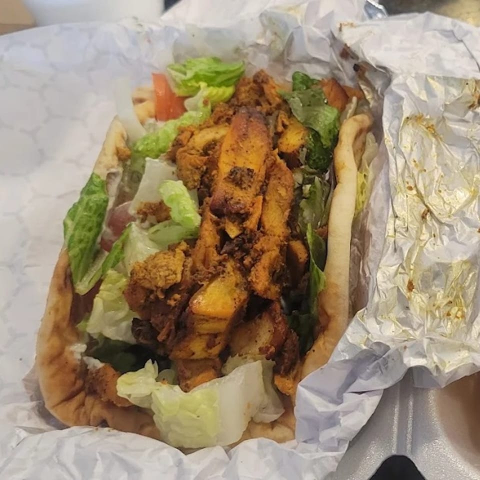King Of Gyros' chicken gyro with lettuce and tomatoes, wrapped in paper and foil.