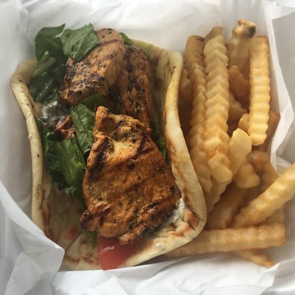 King Of Gyros chicken gyro with lettuce, tomato, and tzatziki sauce, served with crinkle-cut fries.
