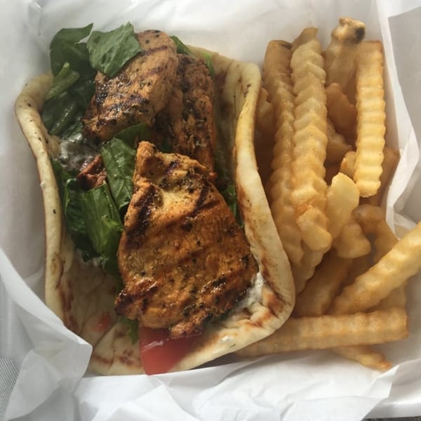 King Of Gyros chicken pita with lettuce, tomato, tzatziki, and a side of crinkle-cut fries.