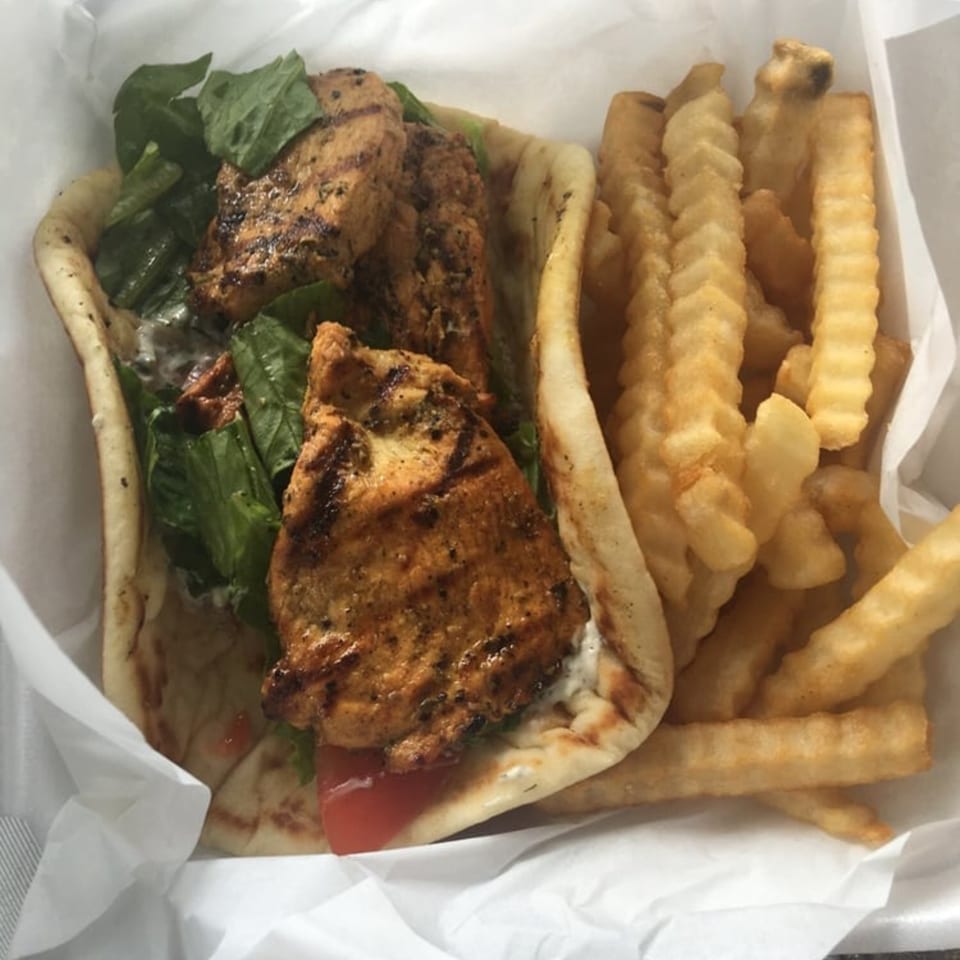 King Of Gyros chicken pita with lettuce, tomato, tzatziki, and a side of crinkle-cut fries.