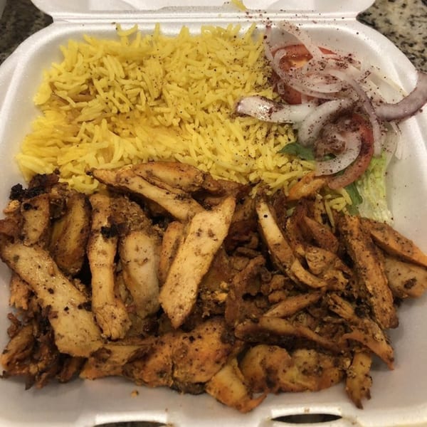 King Of Gyros chicken shawarma plate with yellow rice, sliced onions, tomatoes, and lettuce.