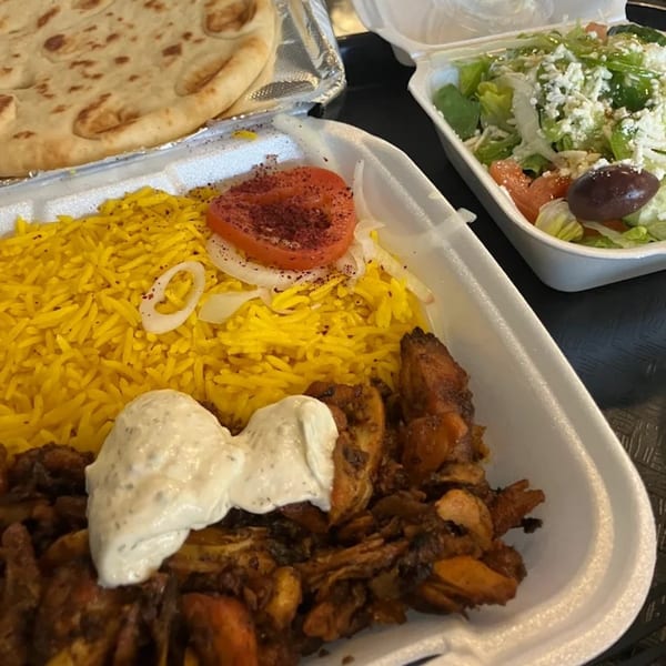 King Of Gyros' chicken over rice with tzatziki, a side salad, and pita bread.