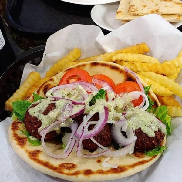 King Of Gyros' falafel pita with lettuce, tomatoes, red onions, tzatziki, and a side of fries.