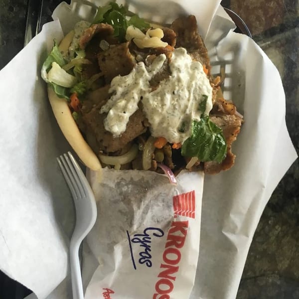 King Of Gyros' gyro with meat, lettuce, onions, and tzatziki sauce in a paper-lined basket.