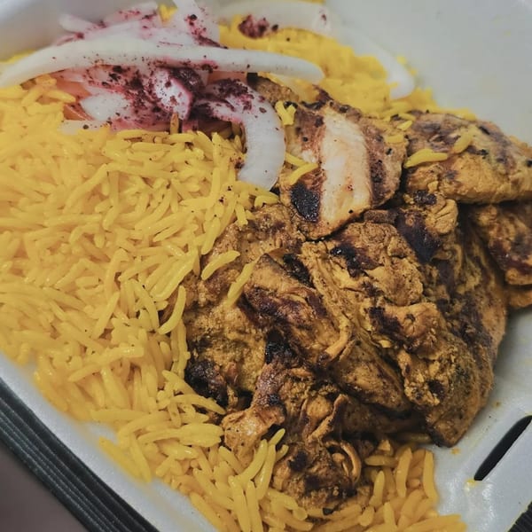 King Of Gyros' grilled chicken with yellow rice and sliced onions, topped with sumac.