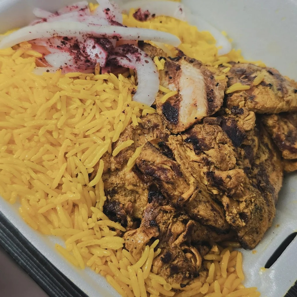 King Of Gyros' grilled chicken with yellow rice and sliced onions, topped with sumac.