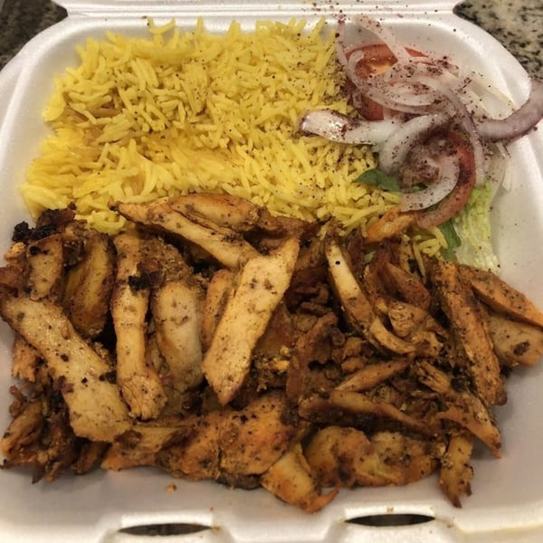 King Of Gyros' chicken shawarma plate with yellow rice, sliced onions, tomatoes, and lettuce.