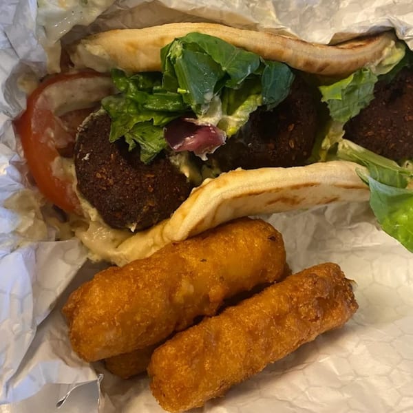 King Of Gyros falafel pita with lettuce, tomato, and sauce, served with fried mozzarella sticks.