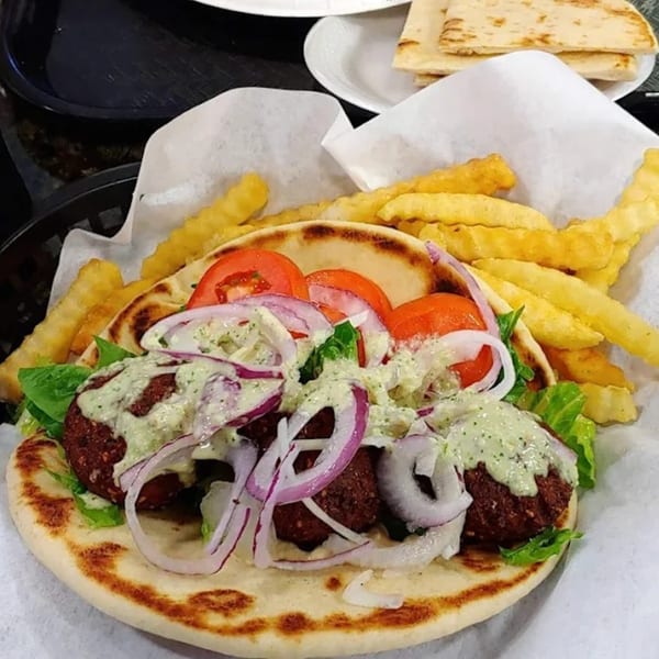 King Of Gyros falafel pita with tomatoes, onions, lettuce, tzatziki, and a side of fries.