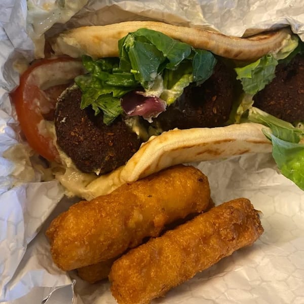 King Of Gyros falafel pita with lettuce, tomato, and sauce, served with fried cheese sticks.