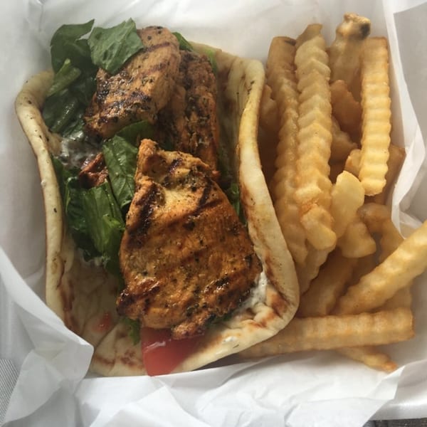 King Of Gyros' grilled chicken pita with lettuce, tomato, tzatziki, and a side of crinkle-cut fries.