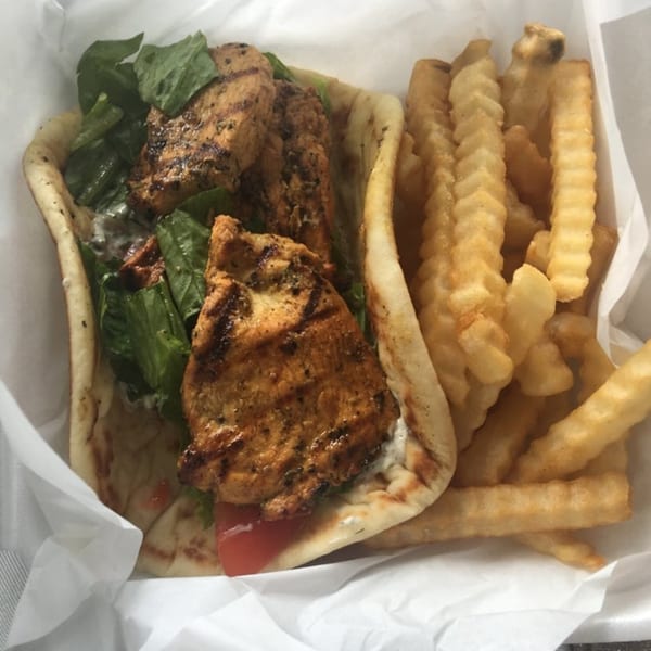 King Of Gyros' chicken pita with lettuce, tomato, and tzatziki, served with crinkle-cut fries.