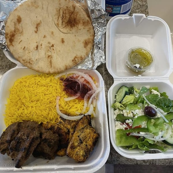 King Of Gyros Greek takeout meal with pita, yellow rice, grilled meats, and a side salad.